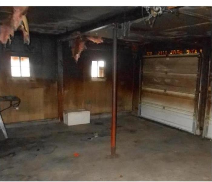 blackened interior of garage, damaged door, hanging insulation