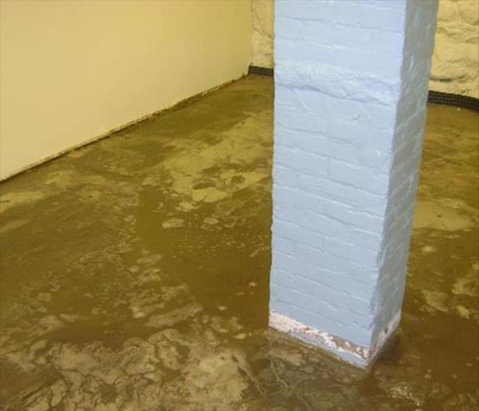 muddy dirt from flood on floor by gray painted brick support column