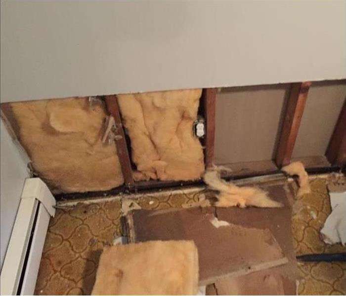 damaged wallboard on floor, showing insulation and studs